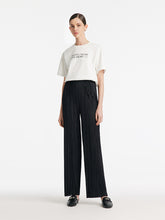 A lady wears pleated straight black pants.